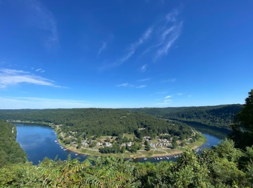 A scenic view of a winding river surrounded by lush green hills under a clear blue sky.