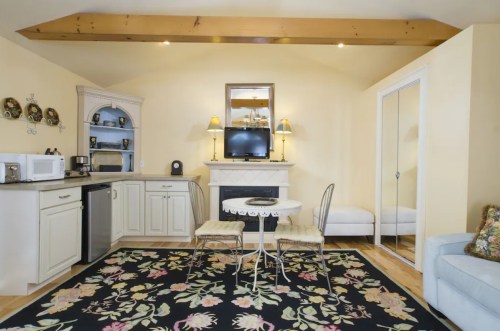 Cozy living space with a kitchenette, dining table, and a decorative rug, featuring soft lighting and a TV.