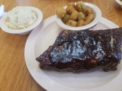 A plate featuring a large piece of glazed ribs, a side of mashed potatoes, and fried okra.