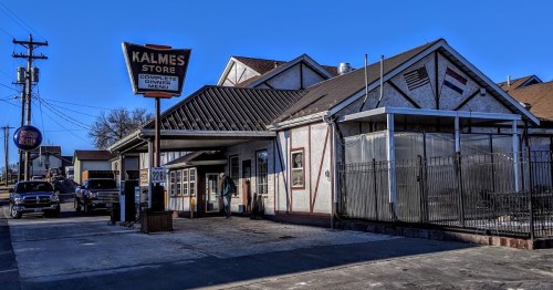 A storefront with a sign reading "Kalmes Store," featuring a covered outdoor area and clear blue sky.
