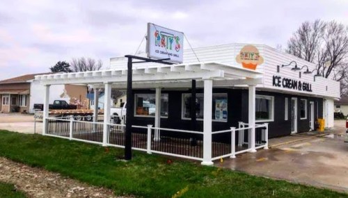 Exterior of an ice cream shop with a white and black facade, featuring a sign that reads "Arty's Ice Cream & Grill."