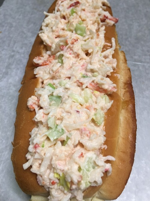 A lobster roll filled with creamy lobster salad and chopped celery on a soft bun.