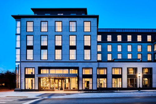 Modern hotel building with large windows, featuring a sleek facade and illuminated entrance at dusk.