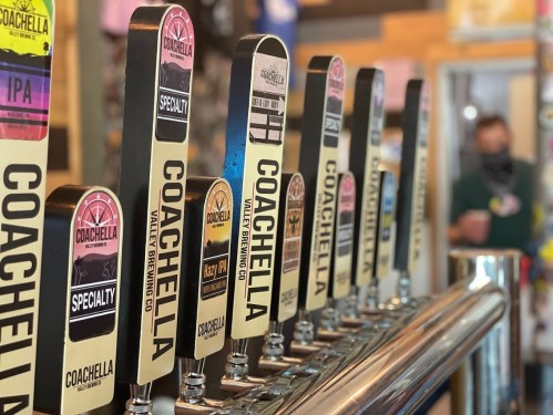 A row of beer taps with Coachella branding, featuring various styles like IPA and Specialty.