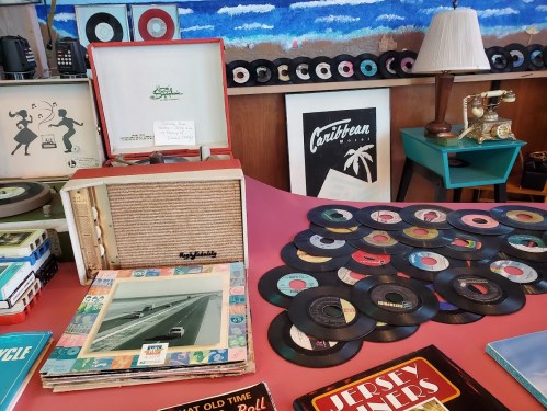 A vintage display featuring records, a record player, and retro decor, with colorful album covers and a scenic background.