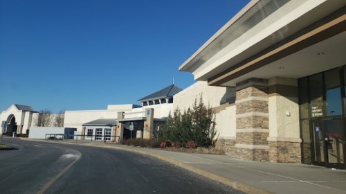 Exterior view of a modern building with a stone facade and clear blue sky in the background.
