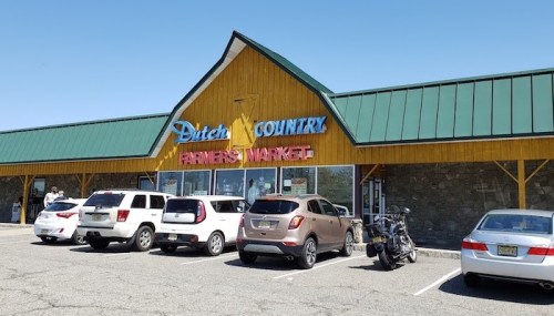 Exterior of Dutch Country Farmers Market with parked cars in front and a clear blue sky above.