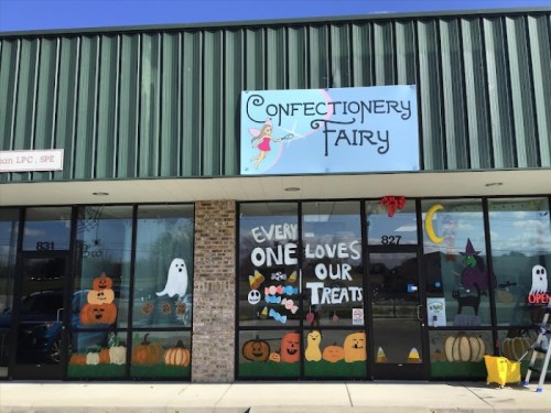 A storefront with colorful Halloween-themed decorations and a sign reading "Confectionery Fairy."