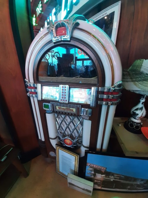 A vintage jukebox with a chrome finish and colorful lights, displayed in a retro-themed setting.
