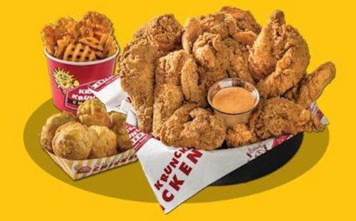 A platter of crispy fried chicken with dipping sauce, accompanied by waffle fries and potato bites on a bright yellow background.