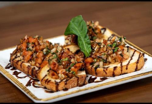 Three slices of grilled bread topped with fresh tomato and basil salsa, drizzled with balsamic glaze, on a white plate.