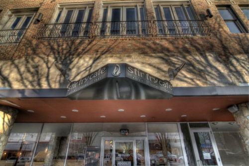 Exterior of Stir Fry Cafe, featuring a canopy and large windows, with tree shadows cast on the brick wall above.