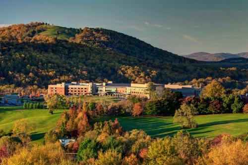 A scenic view of a building surrounded by colorful autumn foliage and rolling hills under a clear sky.
