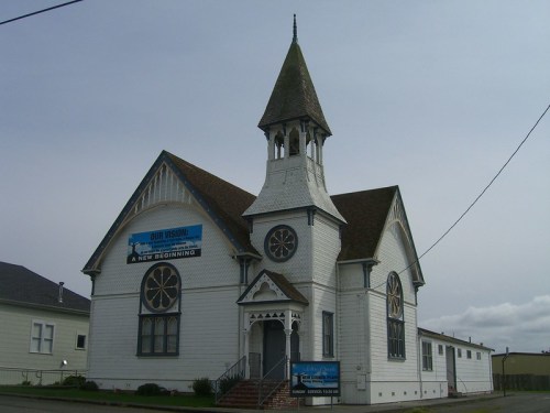 A historic church with a tall steeple, decorative windows, and a sign reading "A New Beginning" on the front.