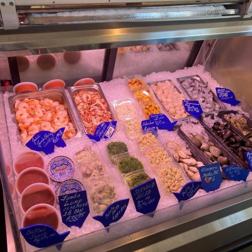 A seafood display case filled with various fresh seafood, including shrimp, crab, and shellfish, on ice with labels.