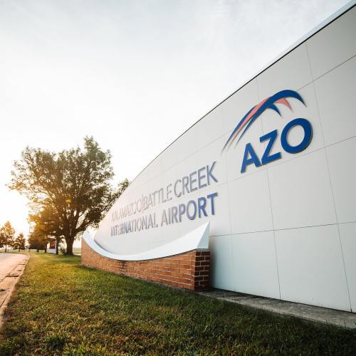 Sign for Kalamazoo/Battle Creek International Airport (AZO) with a tree and sunrise in the background.