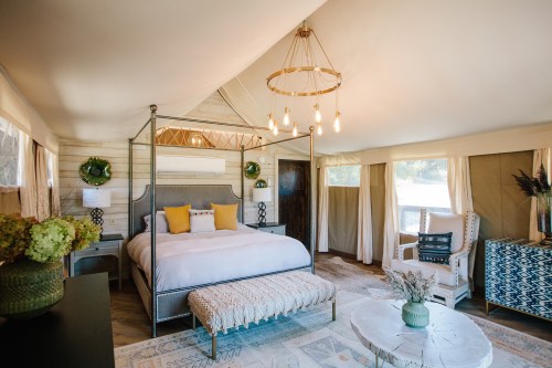 Cozy, stylish tent interior featuring a four-poster bed, seating area, and decorative accents in warm tones.