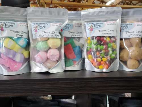 Colorful bags of freeze-dried candies, including taffy, Skittles, and other treats, displayed on a shelf.