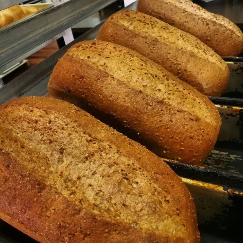 Four freshly baked loaves of whole grain bread cooling on a rack.