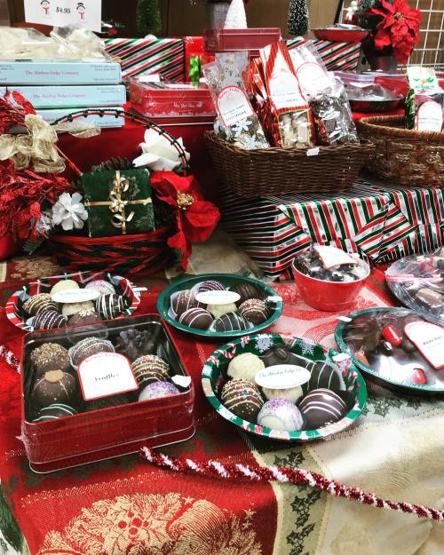 A festive display of assorted chocolates and treats in holiday-themed packaging, surrounded by decorations.