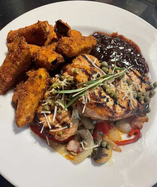 Grilled salmon topped with capers and herbs, served with fried plantains and a side of dark sauce.