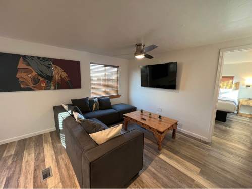 A modern living room with a gray sofa, wooden coffee table, wall art, and a TV mounted on the wall.