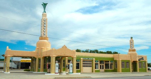Art Deco-style Conoco gas station and café with a tall, decorative tower and vintage gas pumps.