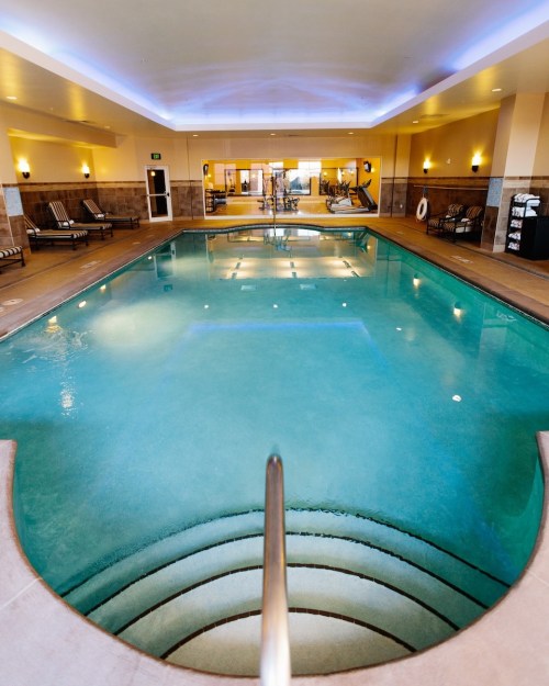 Indoor swimming pool with clear water, lounge chairs, and a well-lit, modern atmosphere.