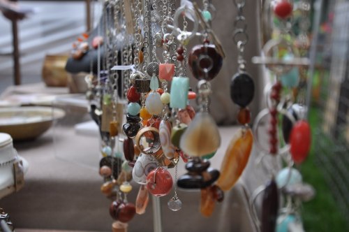 A close-up of colorful handmade jewelry hanging on display at a market, featuring various stones and designs.