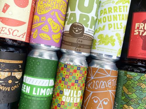 A colorful assortment of craft beer cans with various vibrant designs and labels stacked together.