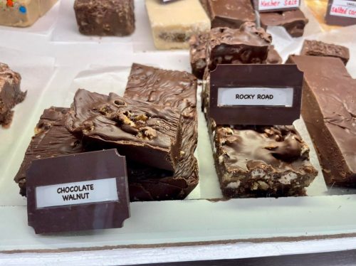 A display of fudge varieties, including Chocolate Walnut and Rocky Road, in a candy shop.