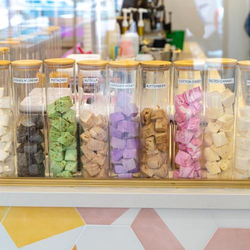 Colorful jars filled with various flavors of fudge, including cookies 'n cream, pistachio, and lavender honey.