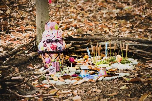 A whimsical outdoor scene featuring a colorful ice cream sculpture surrounded by decorative items and natural elements.