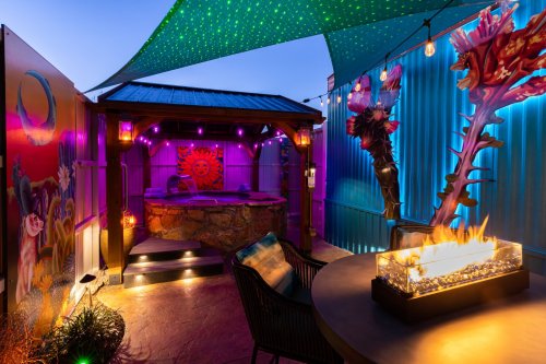 A vibrant outdoor space with a hot tub, colorful lighting, and decorative elements, creating a cozy atmosphere.
