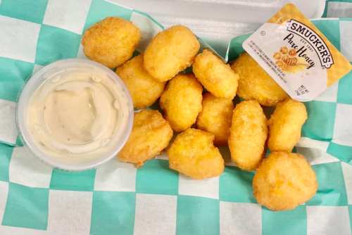 A tray of golden, crispy chicken nuggets with a side of dipping sauce and a packet of Smucker's honey.