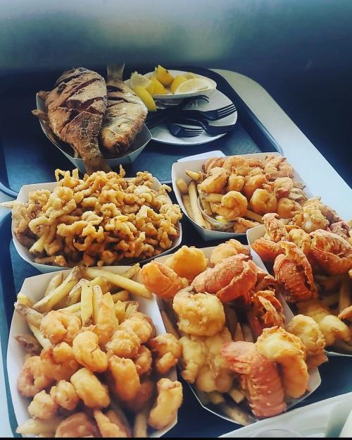 A variety of fried seafood dishes, including shrimp, fish, and fries, served with lemon wedges on a tray.