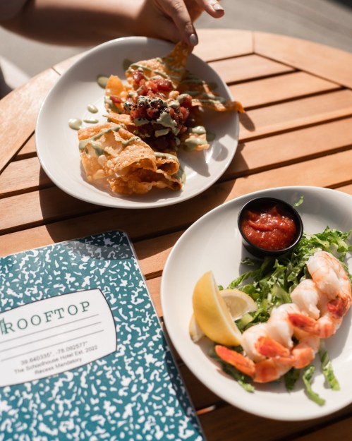 A plate of nachos with toppings and a shrimp dish with salsa and lemon, alongside a menu titled "Rooftop."