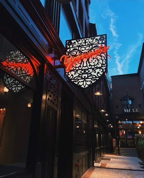 A decorative neon sign reading "Vesper" hangs outside a building, with a blue sky in the background.