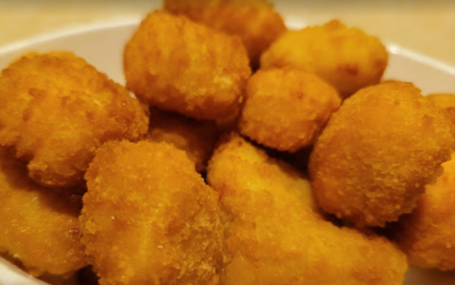 A close-up of golden, crispy chicken nuggets piled in a white bowl.