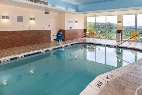 Indoor swimming pool with a scenic view, featuring lounge chairs and a pool lift for accessibility.