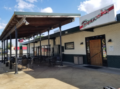 Exterior of Deano's restaurant featuring a covered patio and outdoor seating area under a blue sky.