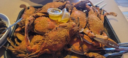 A tray of seasoned crabs with a small container of sauce on the side, ready to be enjoyed.