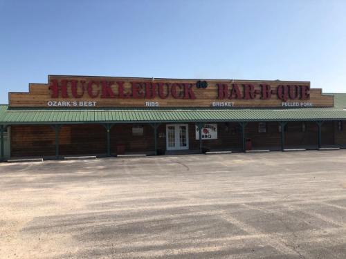 Exterior of Hucklebuck Bar-B-Que restaurant with a wooden facade and signage promoting BBQ, brisket, and pulled pork.