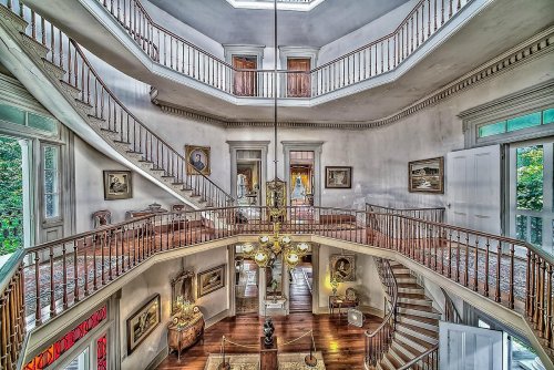 A grand, multi-level foyer with a spiral staircase, elegant decor, and large windows letting in natural light.