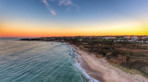 A serene beach at sunset, with gentle waves lapping the shore and a colorful sky above.