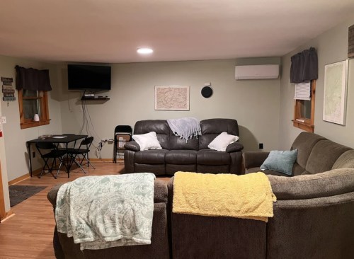 Cozy living room with two sofas, a TV on the wall, and a small dining table in a warm, inviting space.