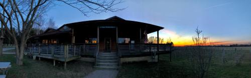 A panoramic view of a building at sunset, with a grassy area and trees in the foreground.