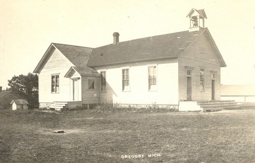 Historic schoolhouse in Gregory, Michigan, featuring a bell tower and surrounded by grassy land.