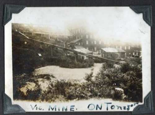 Historic black-and-white photo of Vic Mine in Ontario, featuring buildings and a sloped landscape.