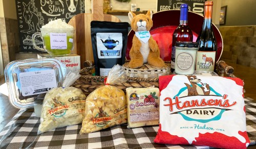 A display of Hansen's Dairy products, including cheese, tea, wine, and a stuffed animal, arranged in a basket.